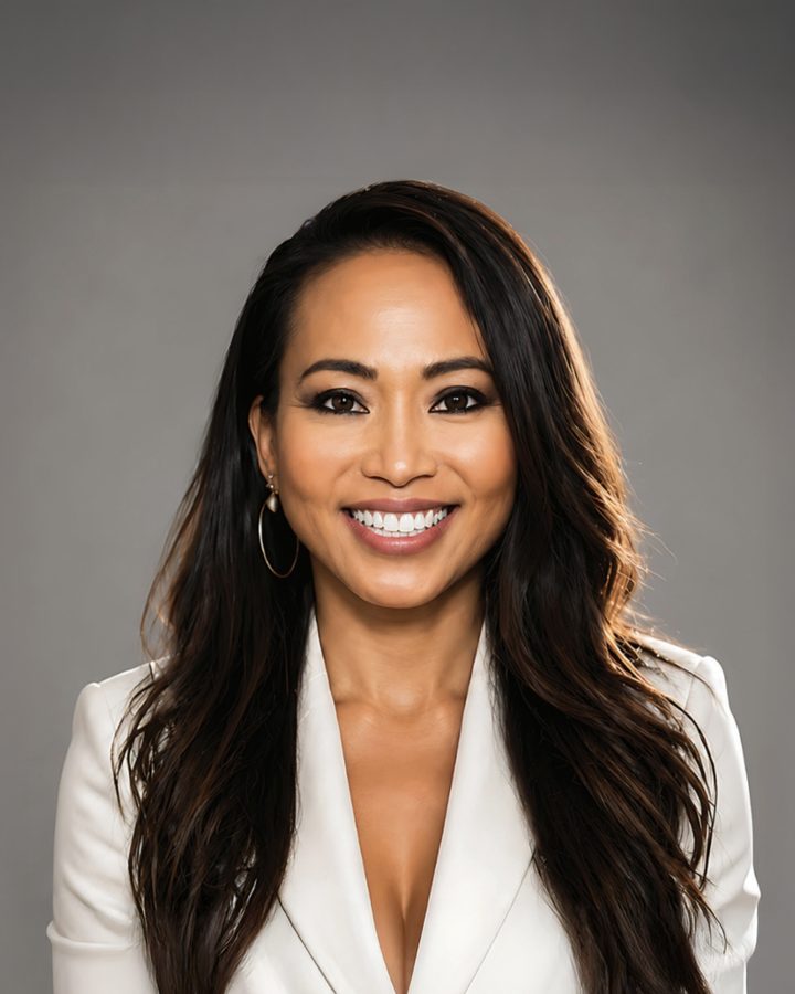Amy Phan West, smiling, in a white blazer against a grey studio backdrop.
